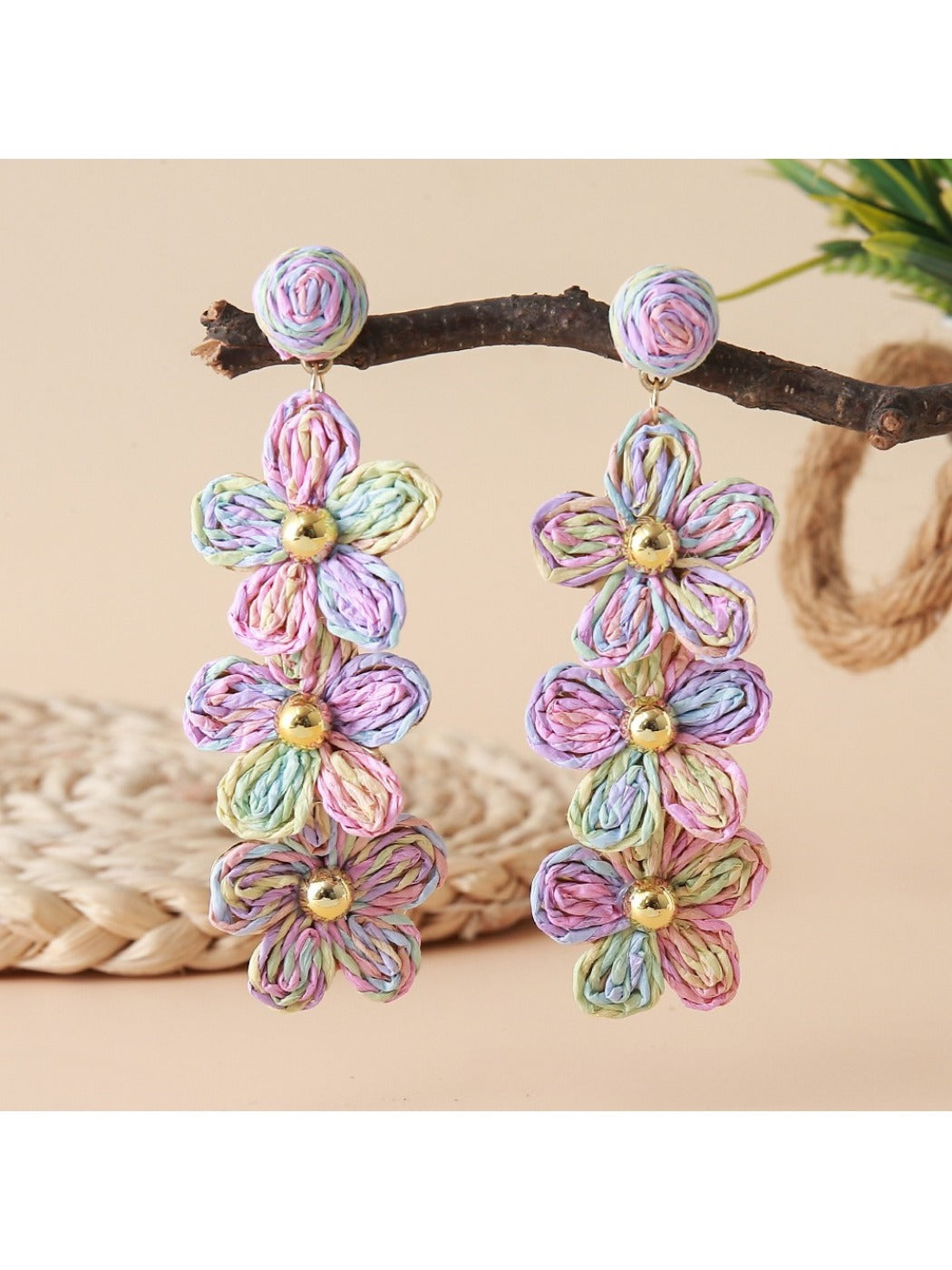 Earedge flower shaped raffia drop earrings displayed with green leaves background