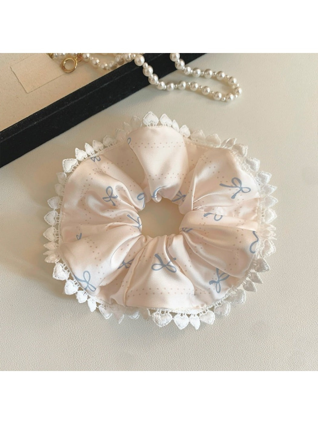 Side view of Gifty satin scrunchie featuring pink bow pattern