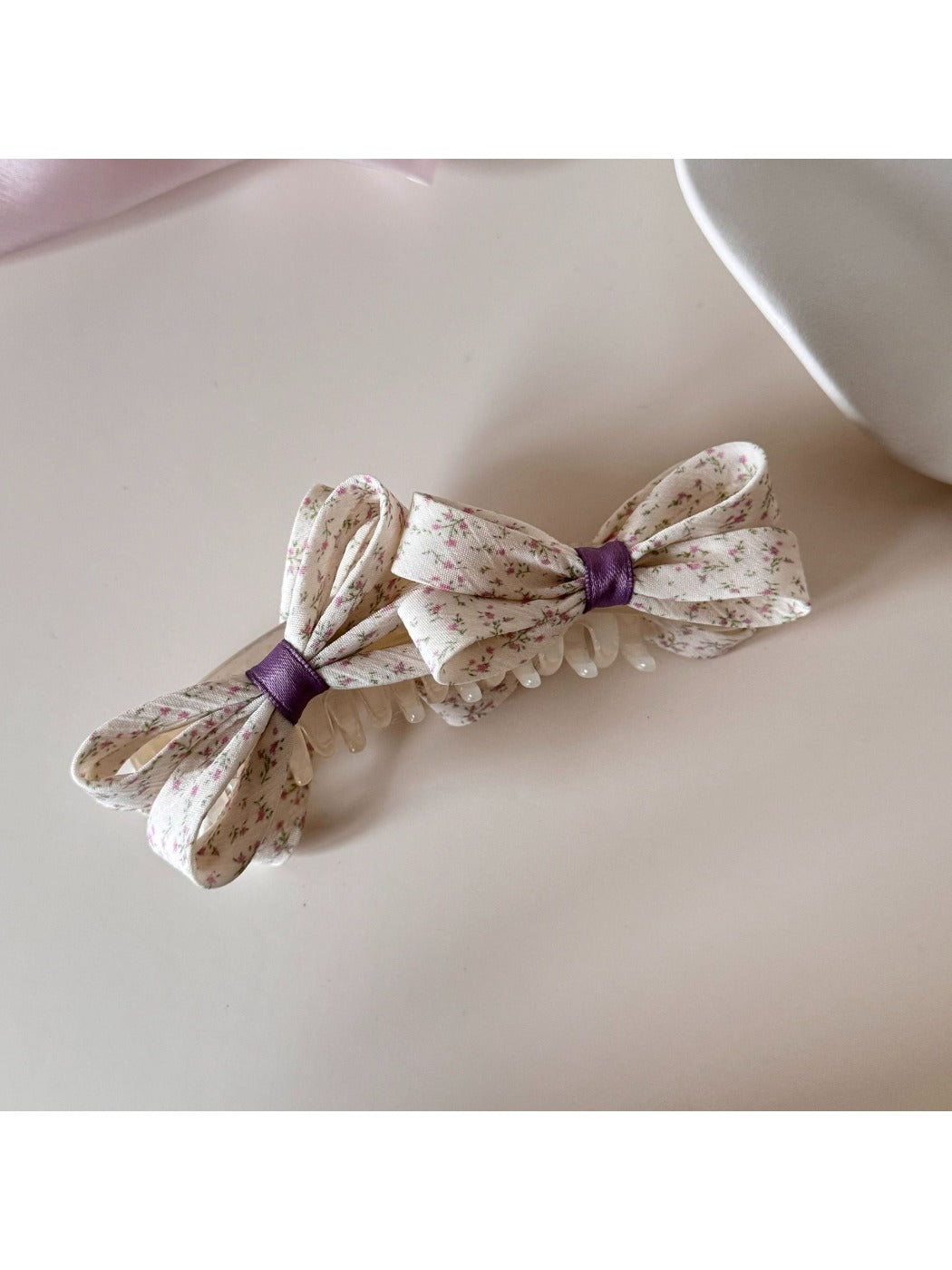 Model wearing Beau printed bow banana clip with floral dress in outdoor setting