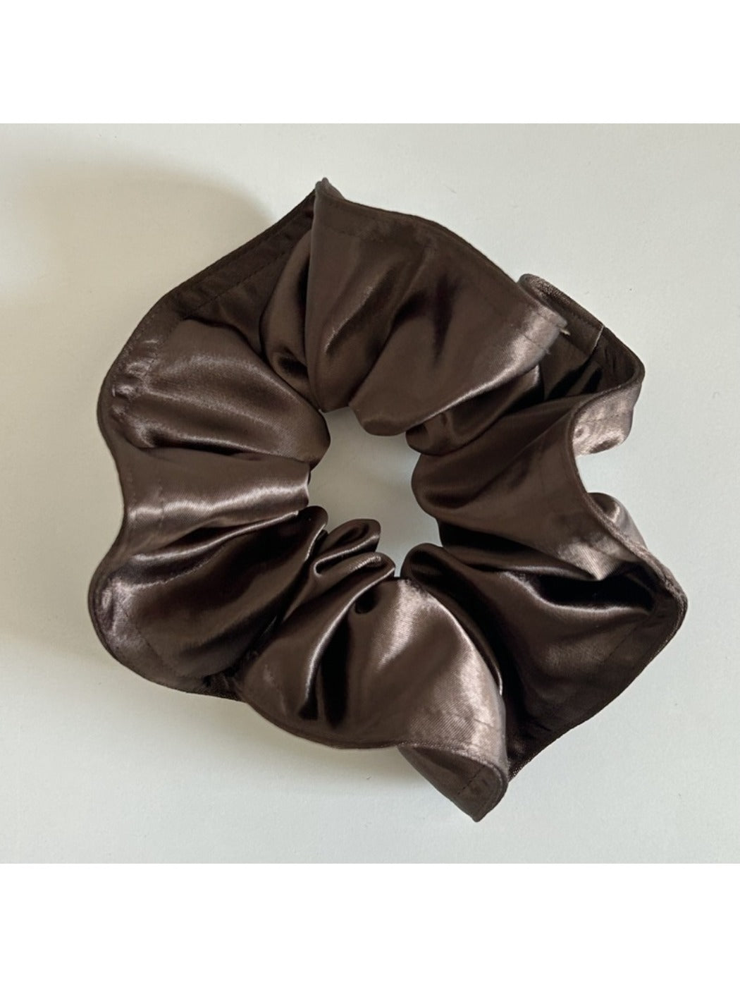 Model adjusting Gifty satin scrunchie in hair with natural outdoor lighting