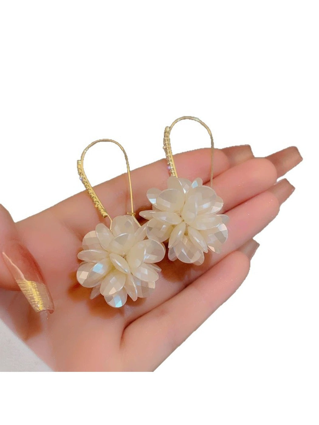 Hydrangea shaped drop earrings hanging from a jewelry stand with soft lighting