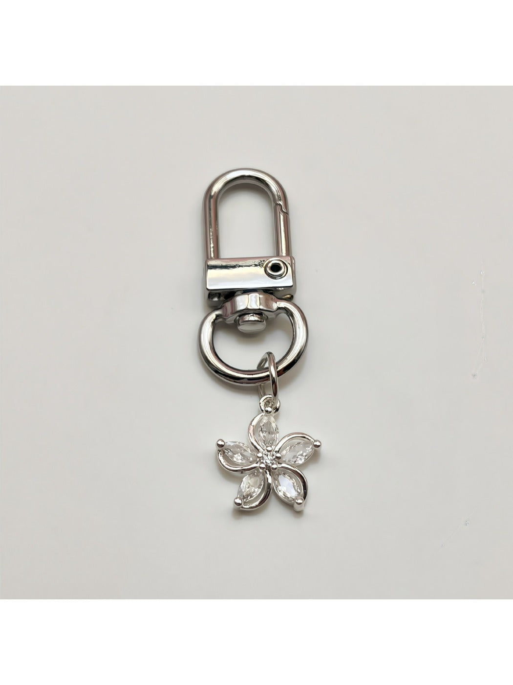 Keypus flower charm keychain placed next to a smartphone and wallet on a table