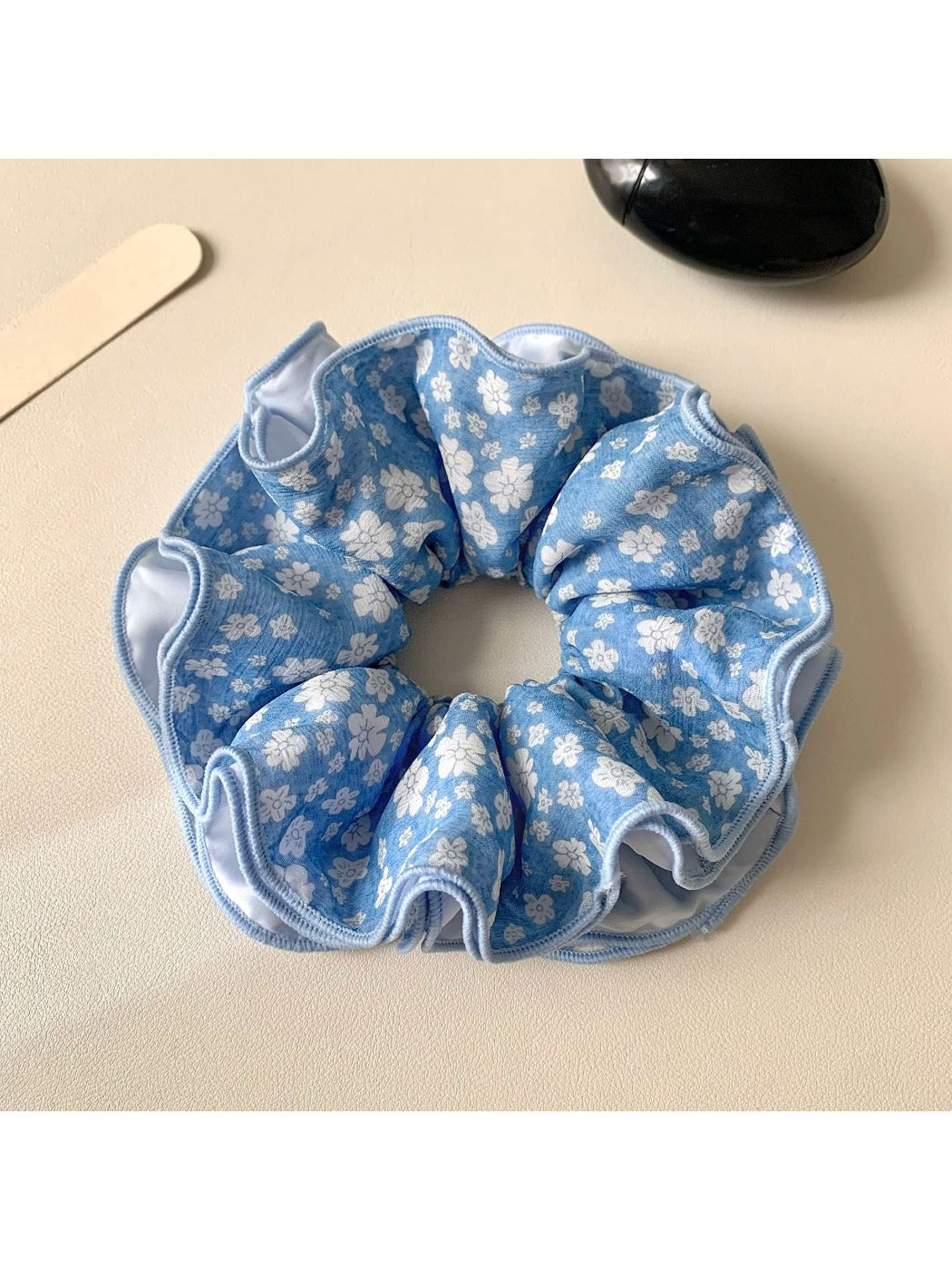 Blue floral pattern scrunchie with pastel colors and gathered fabric design