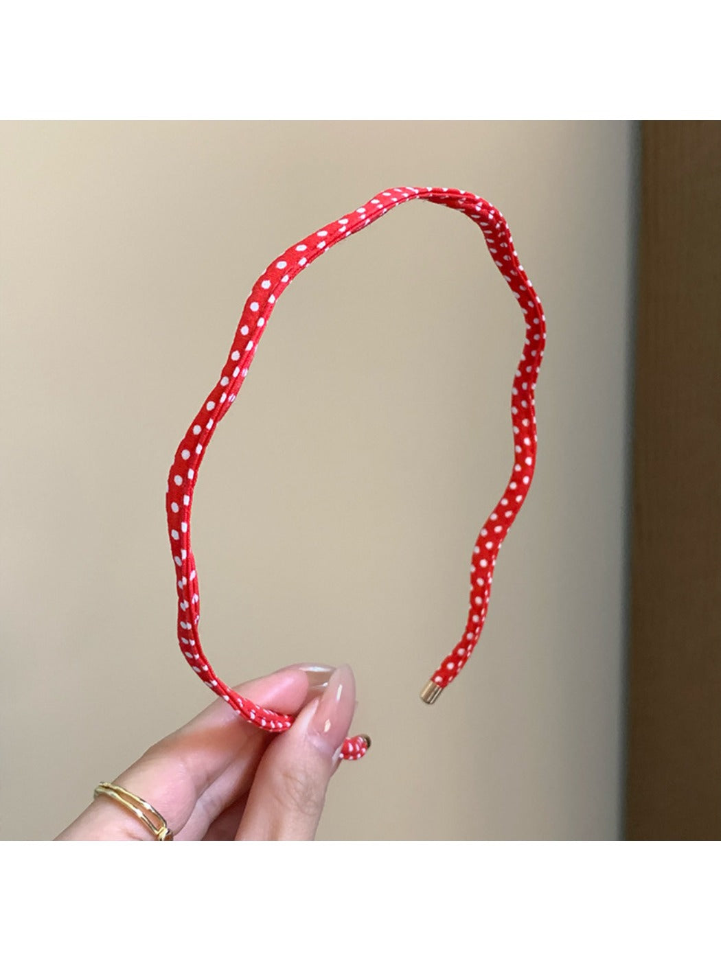 Thin wavy headband displayed flat showing black polka dots on white fabric