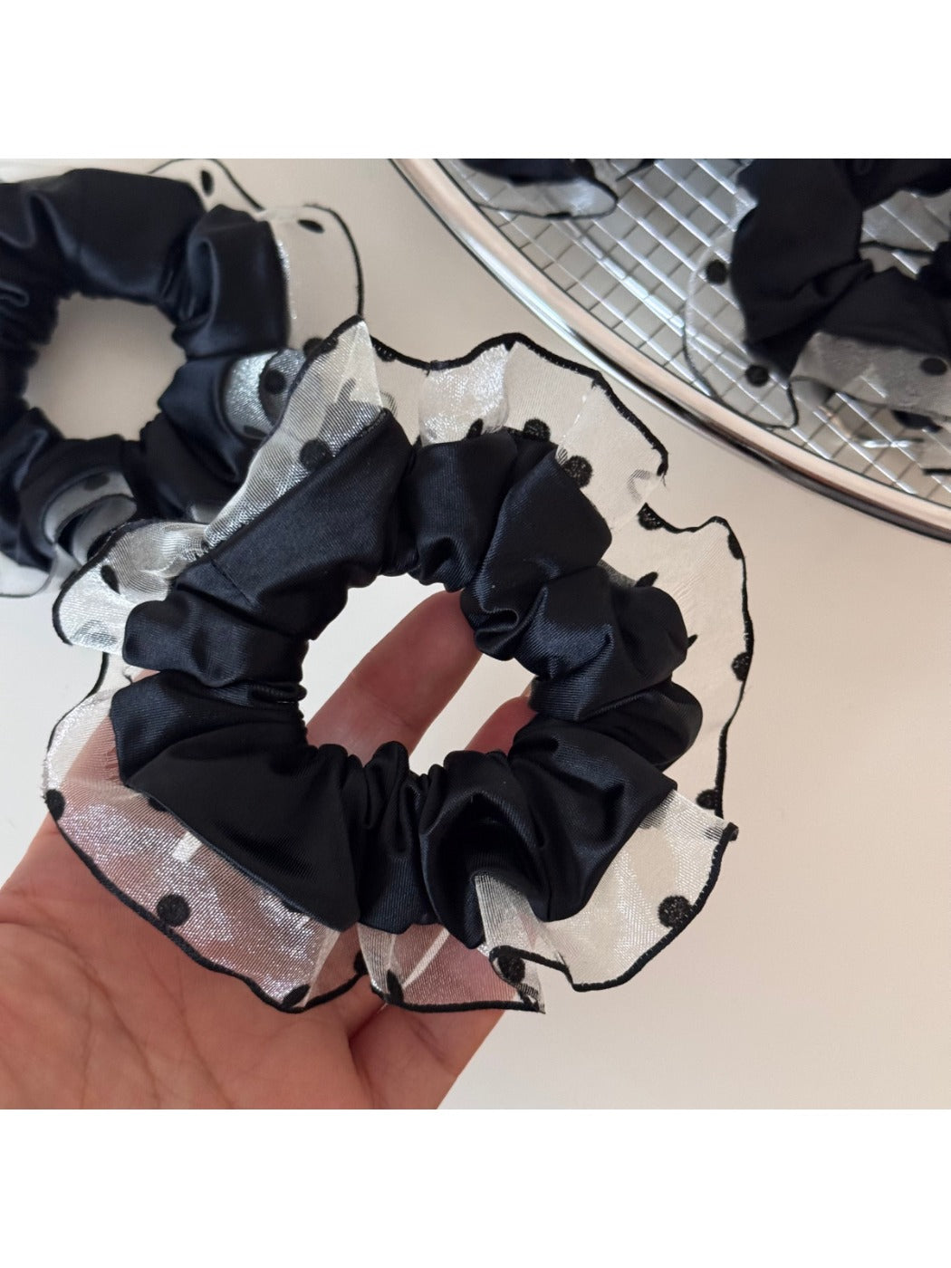 Black scrunchie with white polka dot trim displayed flat