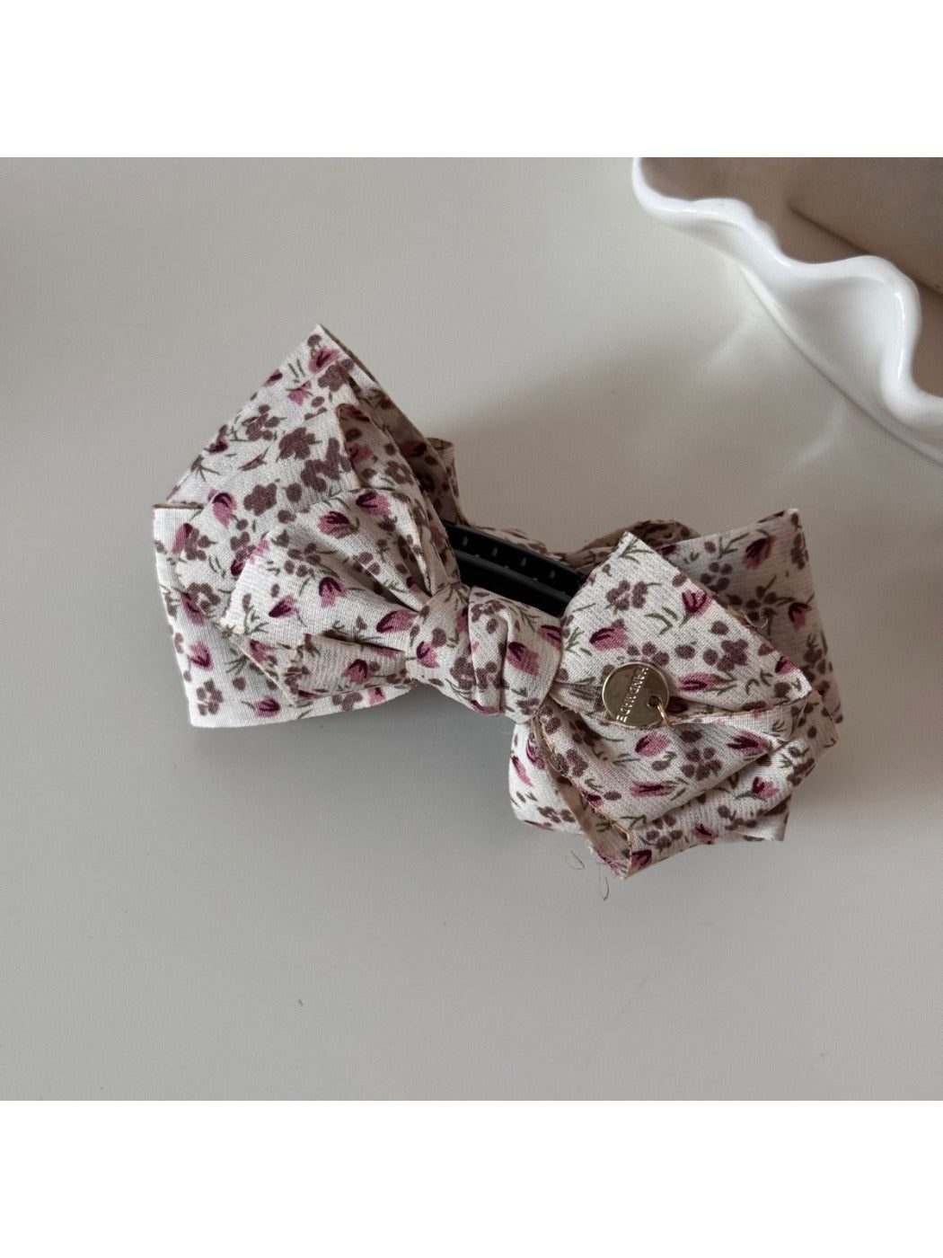 Beau floral print bow hair clip placed next to matching accessories