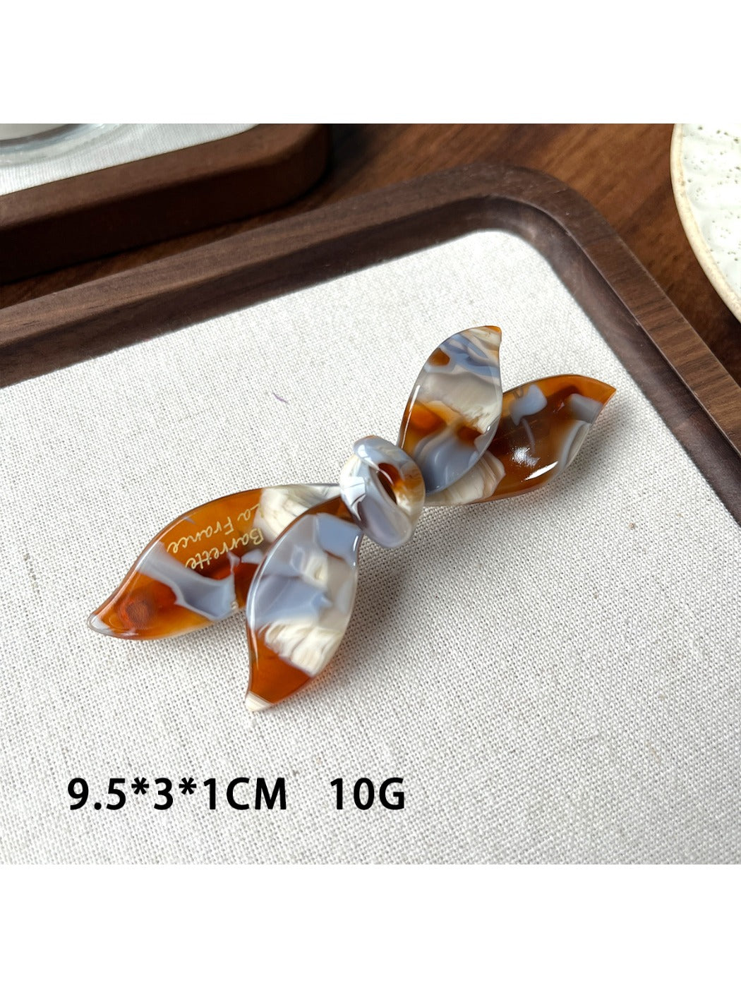 Beau bow shaped updo hair clip photographed on a wooden surface
