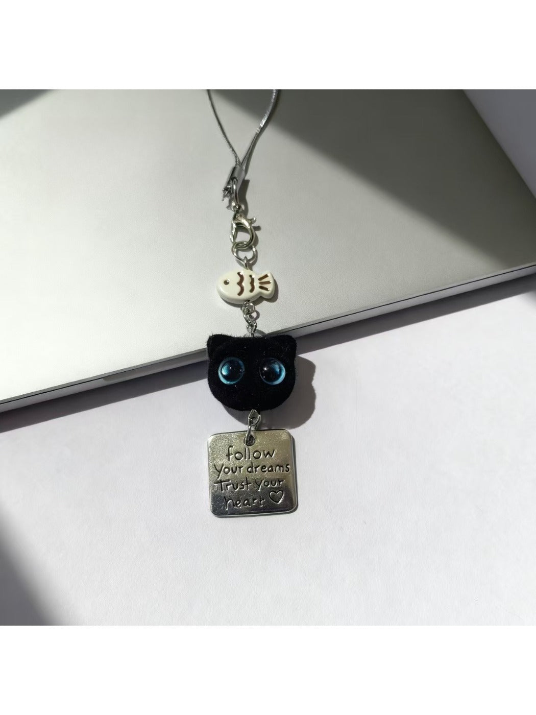 Blue eyed black cat keychain displayed on a white background