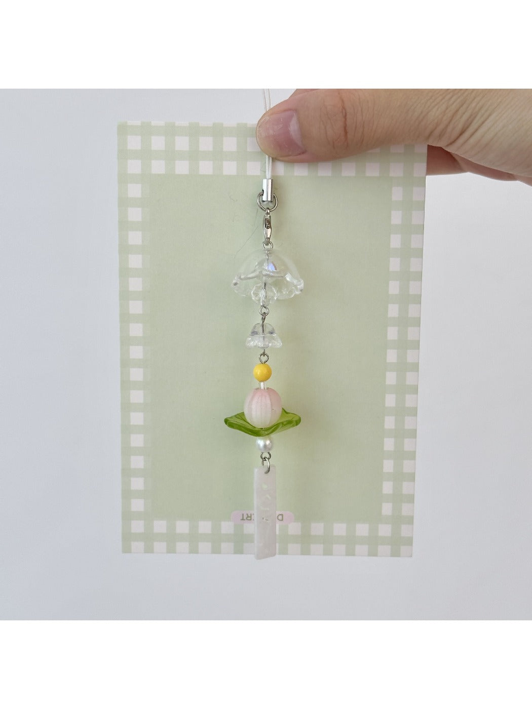 Lotus wind chime keychain hanging from a bag strap outdoors