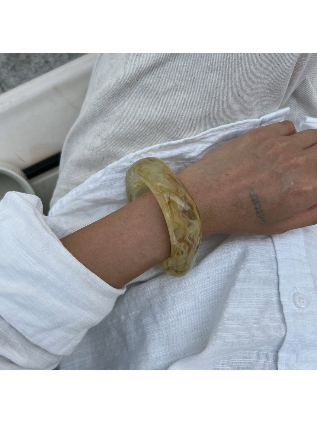 Lovra irregular shaped bangle bracelet resting on a neutral fabric background