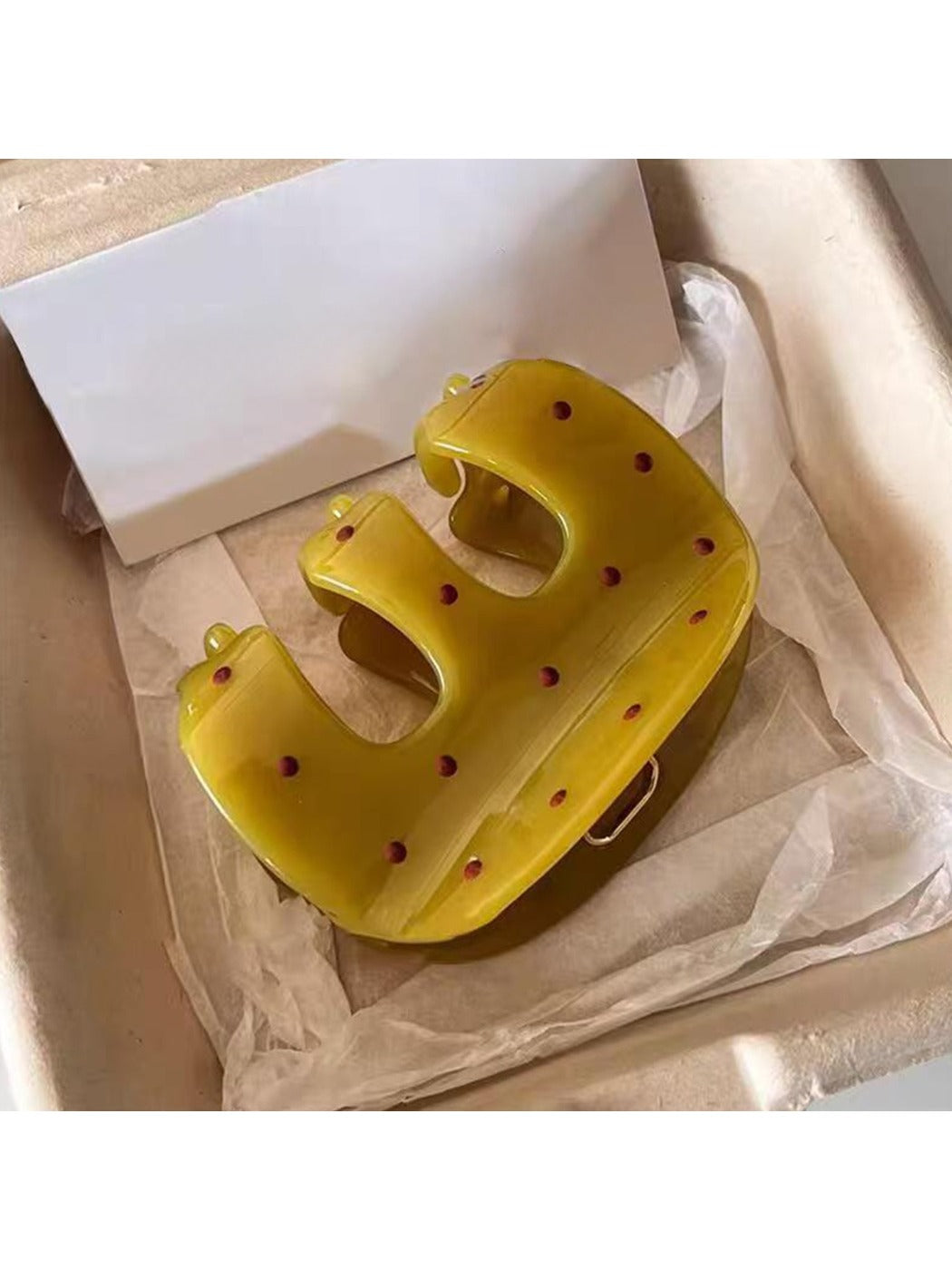 Beau yellow polka dot claw clip holding a section of blonde hair