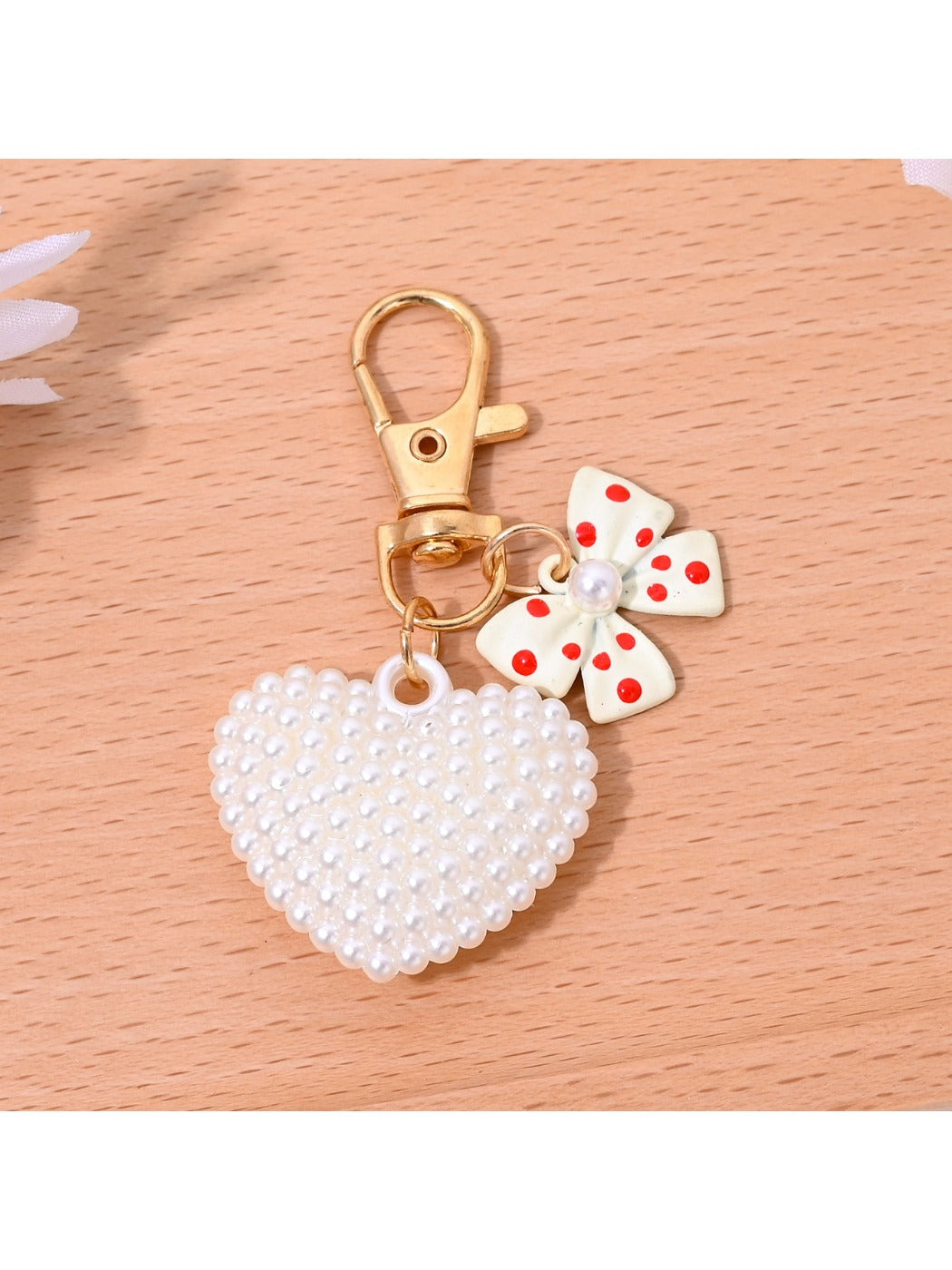 Heart shaped bag charm keychain with gold hardware hanging from a purse strap