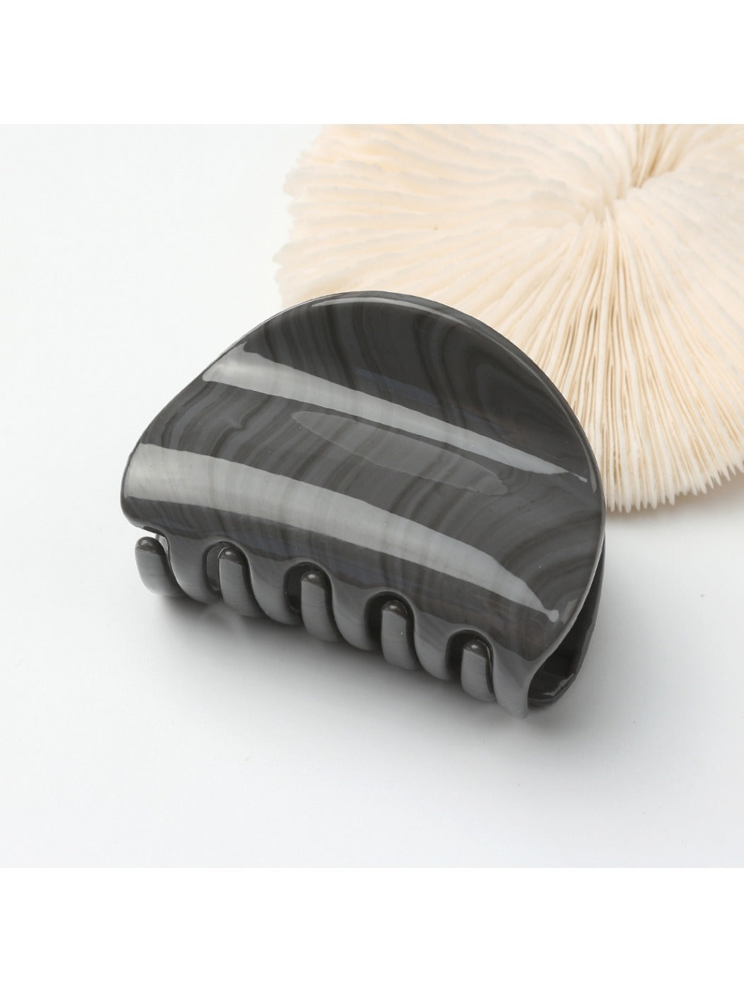 Beau half circle hair clip styled in a low ponytail on dark hair