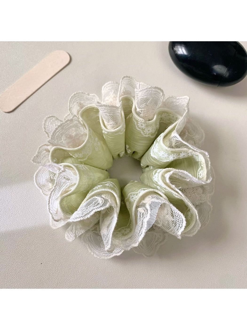 Green lace scrunchie with fresh floral pattern on a white background