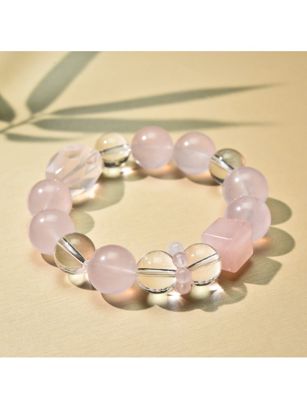 Pink beaded bracelet with gold details laid flat on a textured surface