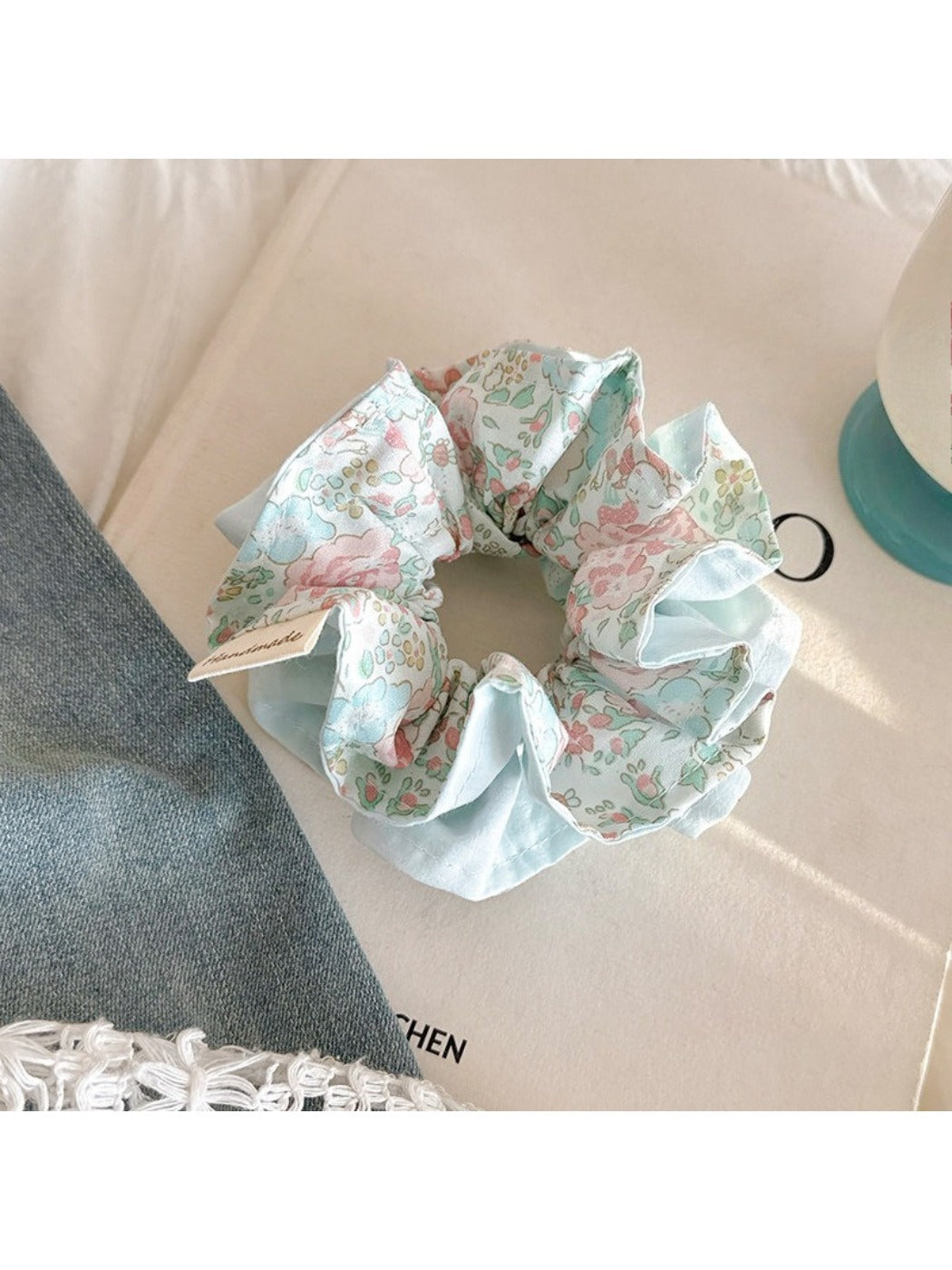 Blue scrunchie with ruffled edges held in a hand