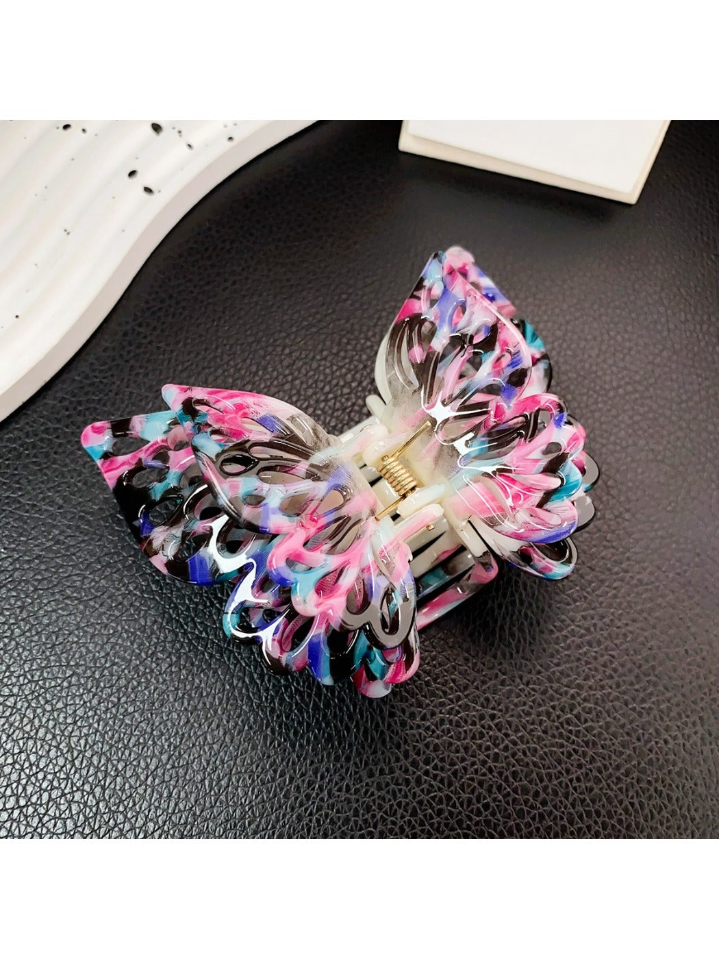 Beau double layer hollow bow shaped claw clip placed on wooden surface
