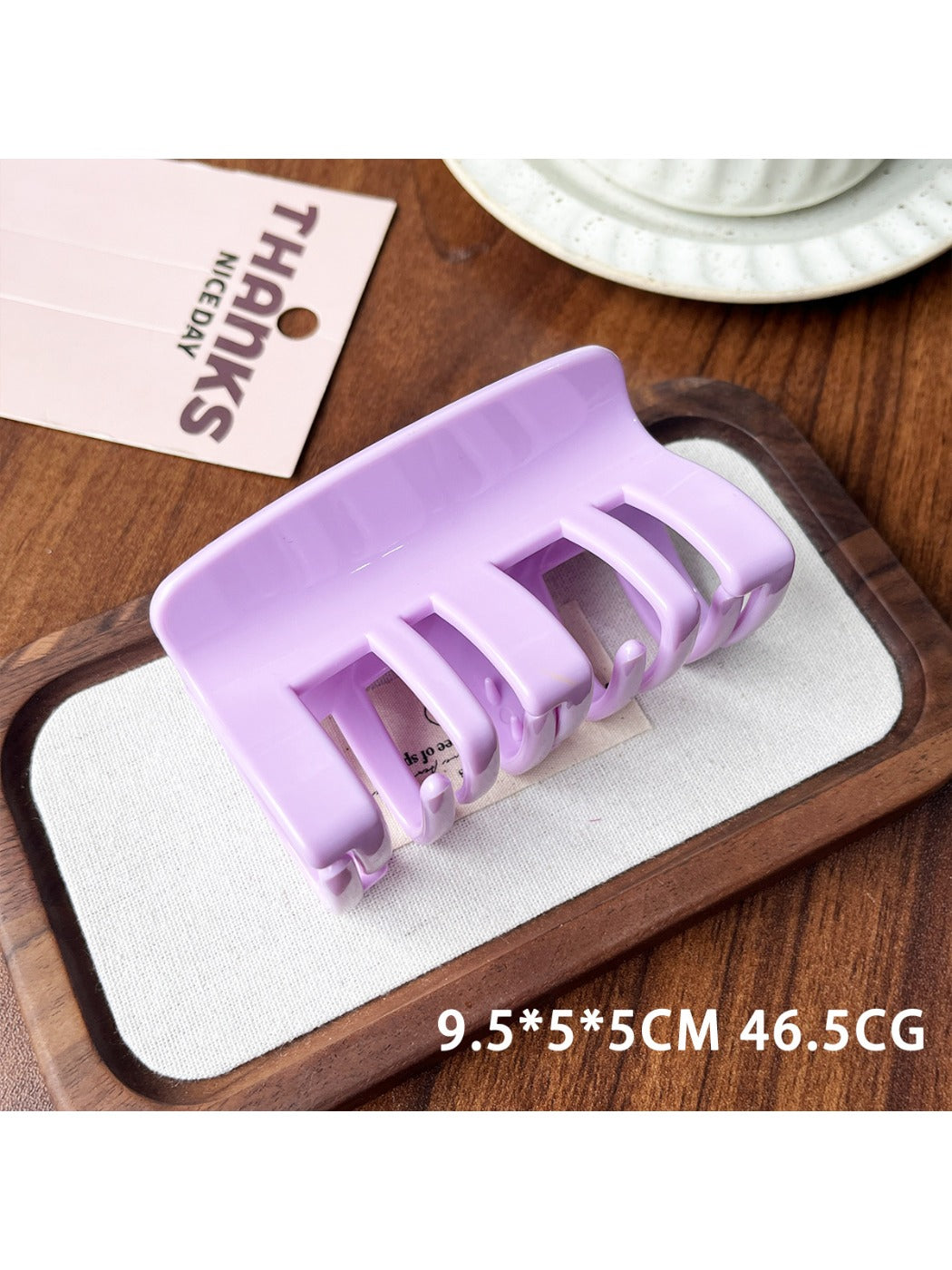 Beau plastic square claw clip resting on textured fabric background
