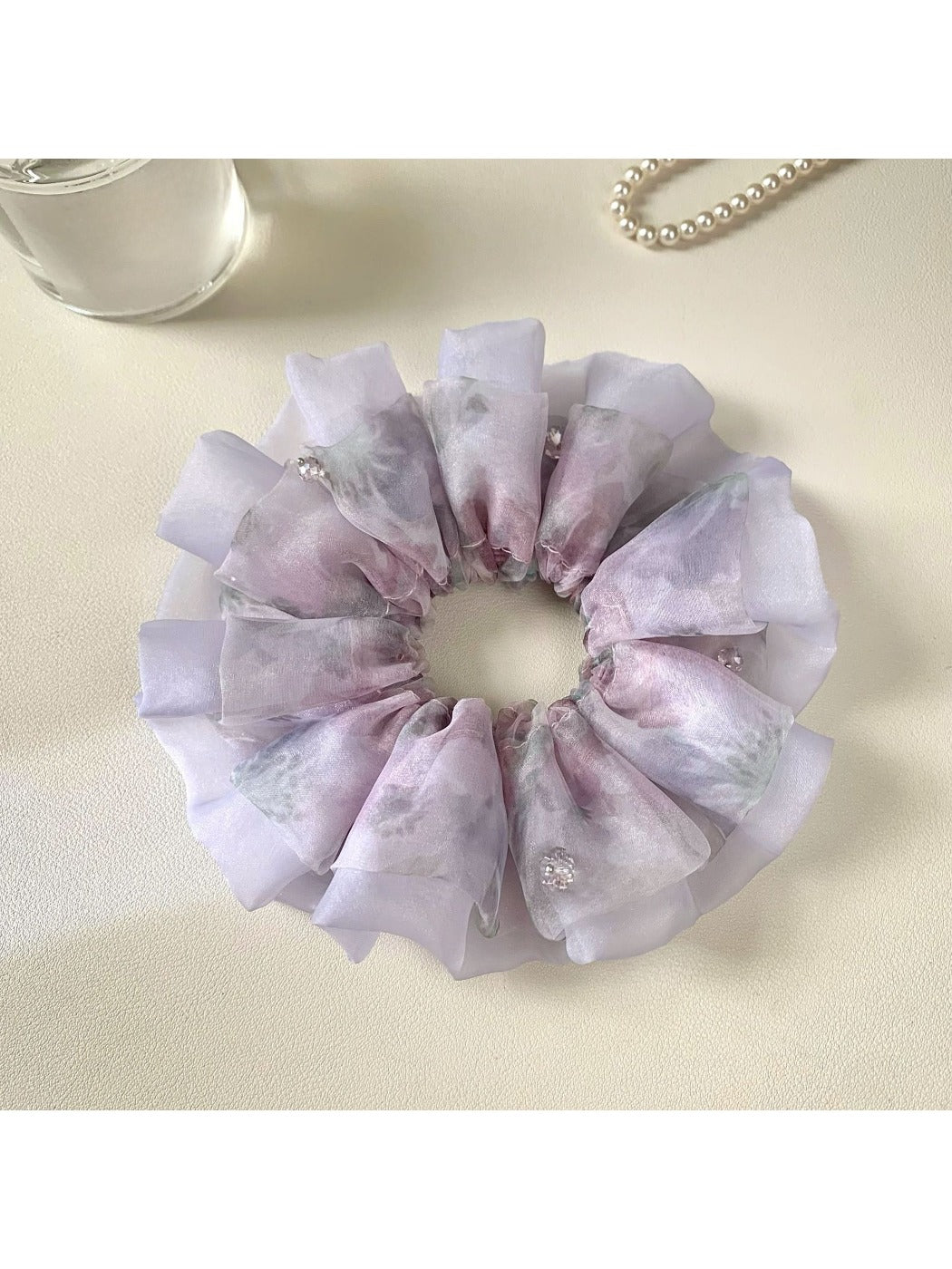 Purple printed scrunchie styled with casual outfit on a wooden surface
