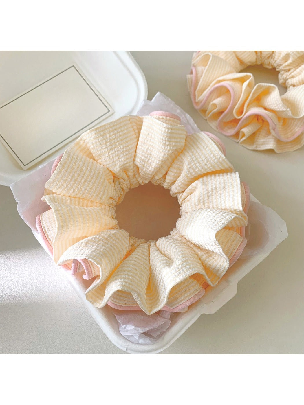 Pink ruffle beige scrunchie styled in a ponytail on a model