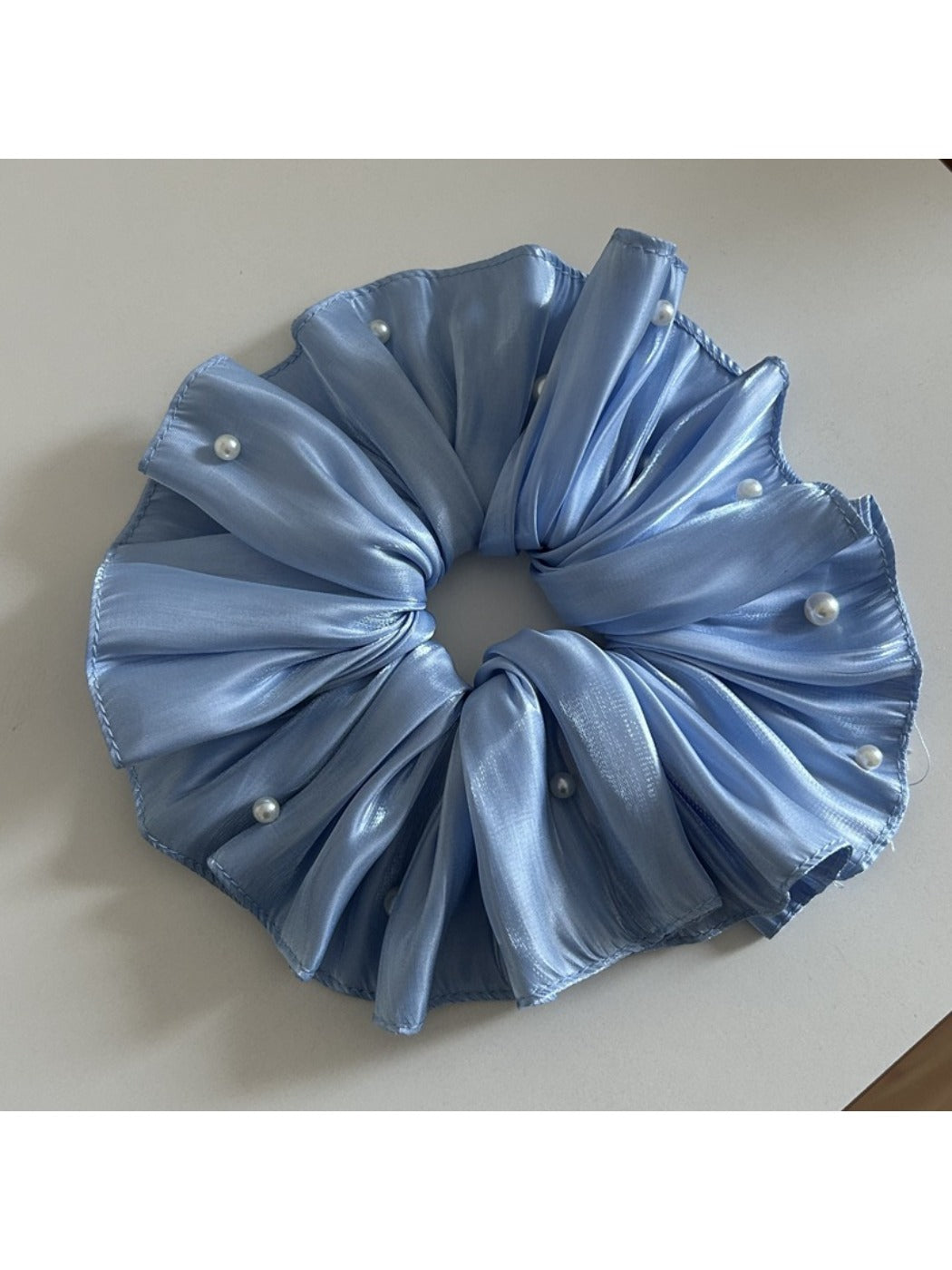 Large satin scrunchie in beige color with a subtle sheen under soft lighting