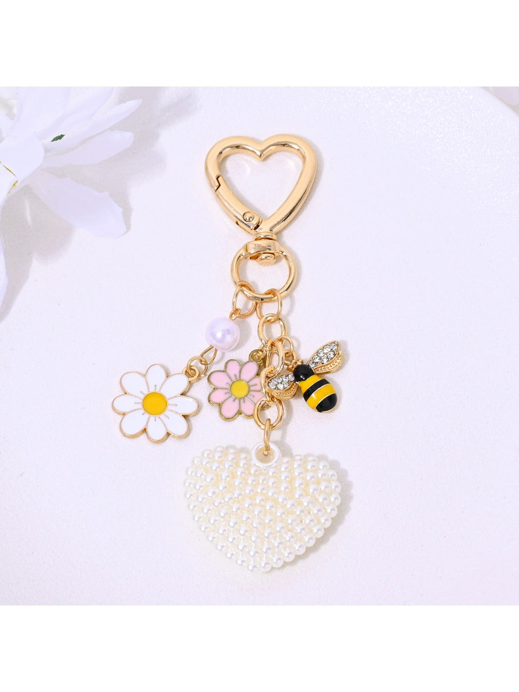 Heart shaped keychain covered in rhinestones with metal keyring on neutral background
