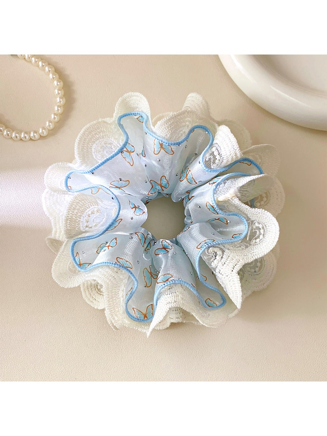 Close-up of blue fabric scrunchie featuring intricate lace edging