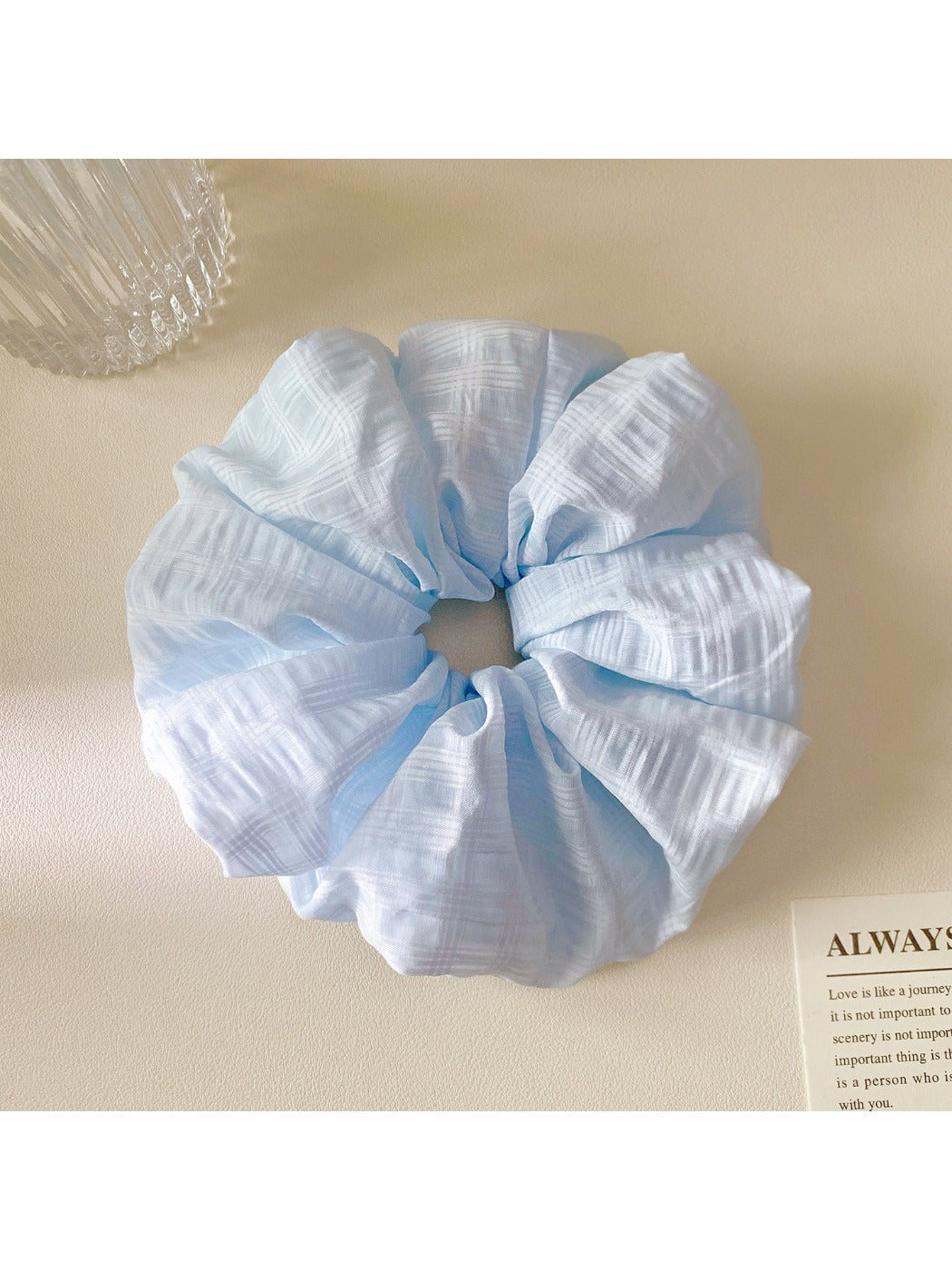 Gifty scrunchie placed on a white surface, showcasing its bright multicolor checkered pattern