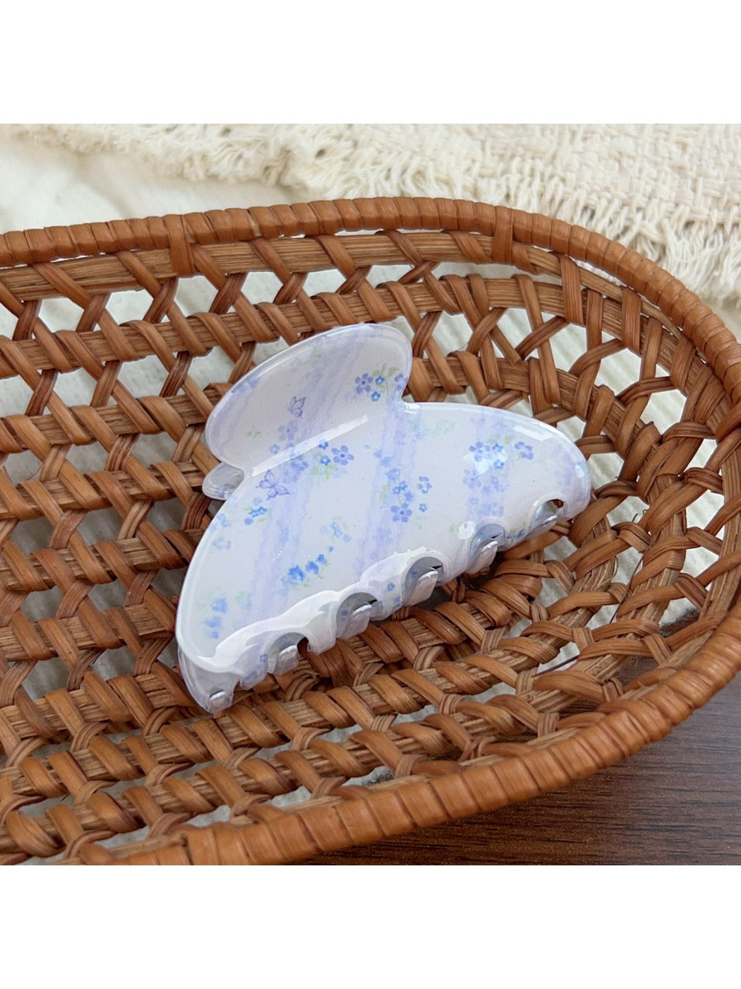 Beau hair claw clip with blue floral print against soft fabric background