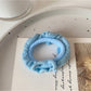 Ruffled hair ties in bright colors displayed in a small glass bowl