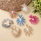 Earedge raffia drop earrings hanging from a jewelry stand
