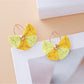 Vintage fan shaped raffia earrings hanging from a jewelry stand