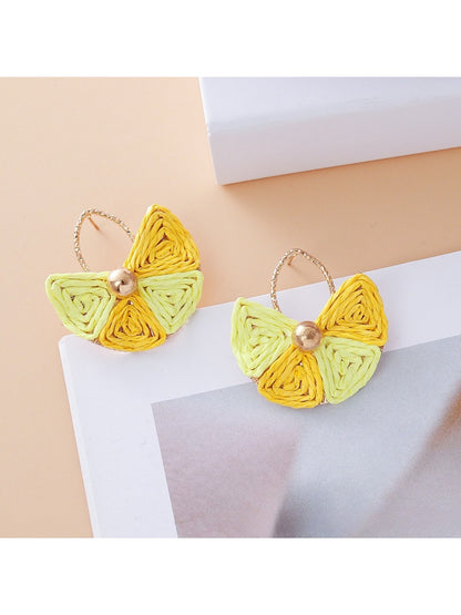 Vintage fan shaped raffia earrings hanging from a jewelry stand
