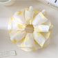 Yellow scrunchie with white polka dots on a white background