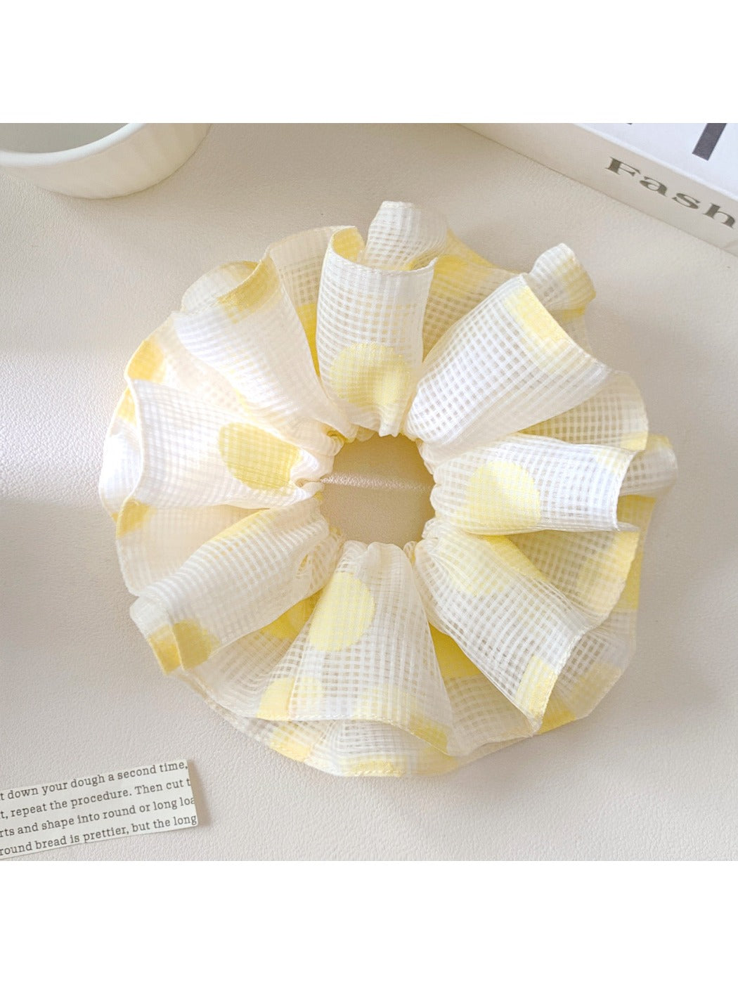 Yellow scrunchie with white polka dots on a white background