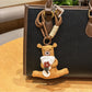 Bear keychain with a smiling expression holding a pink flower close-up