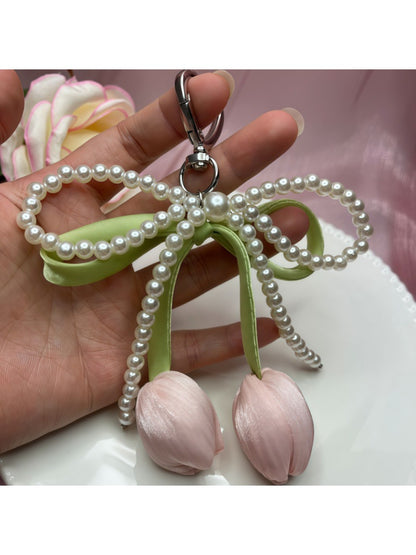 Keychain held in hand showing size and design of bow and tulip pendant