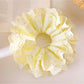 Gifty yellow ruffle scrunchie displayed flat showing gathered fabric details