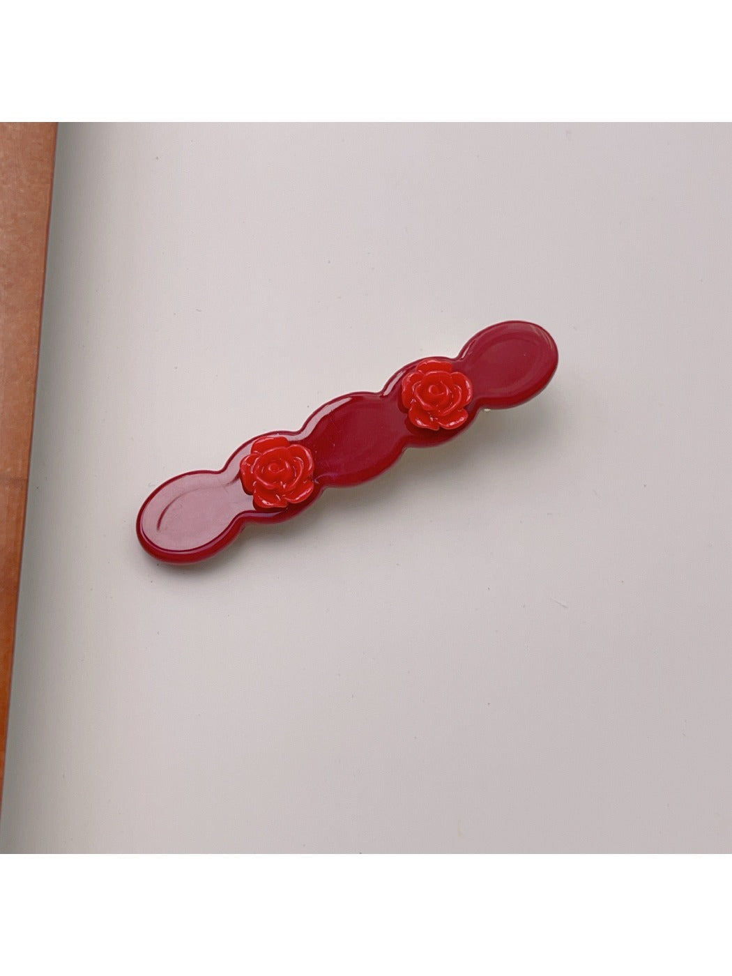 Beau rose decorated wavy hair clip displayed on a wooden surface