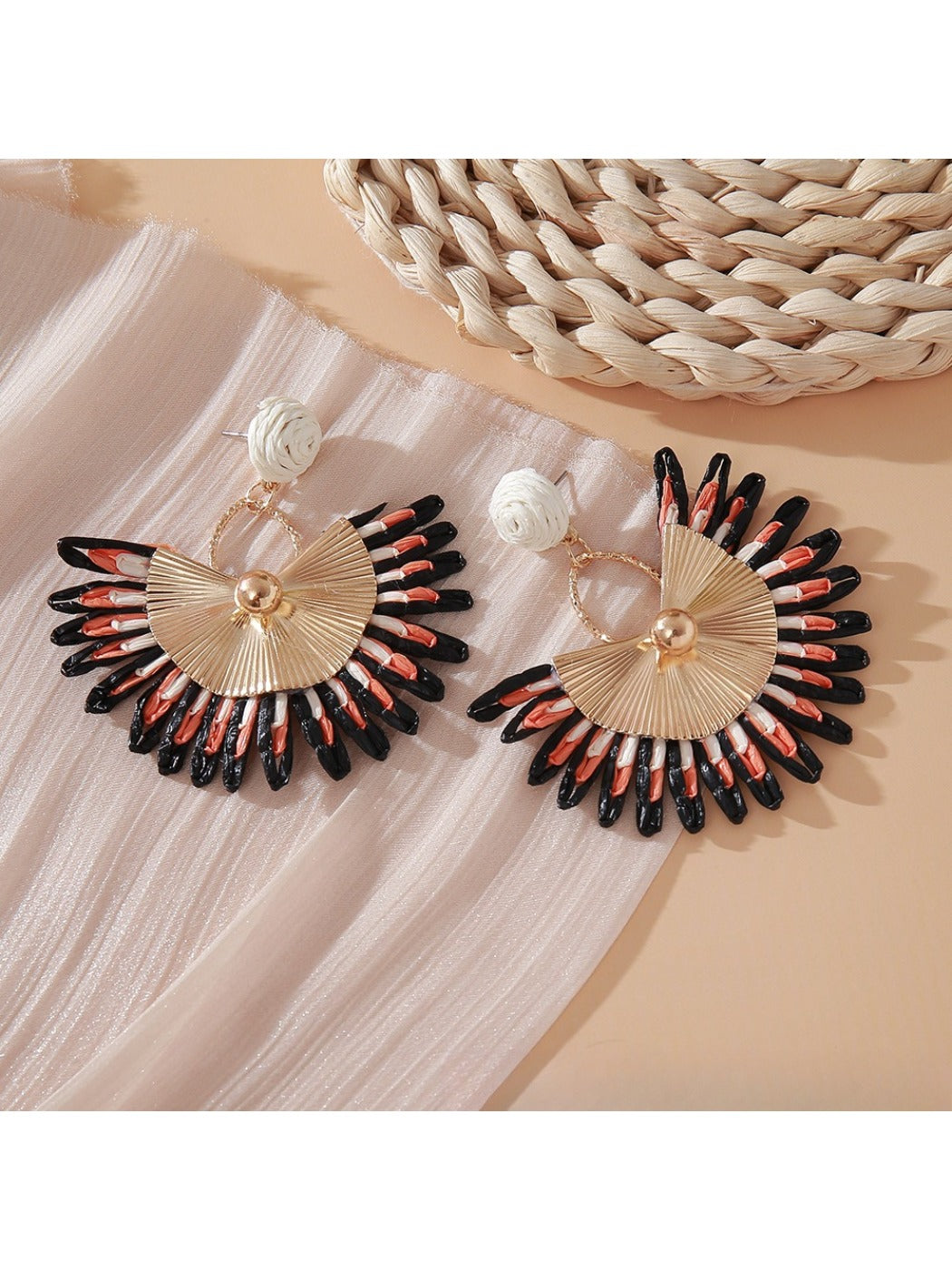 Pink and black raffia woven earrings hanging from gold-tone hoops