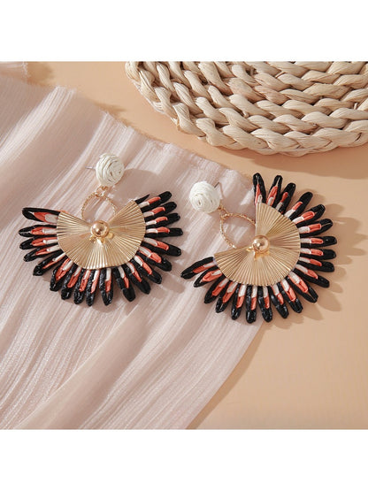 Pink and black raffia woven earrings hanging from gold-tone hoops
