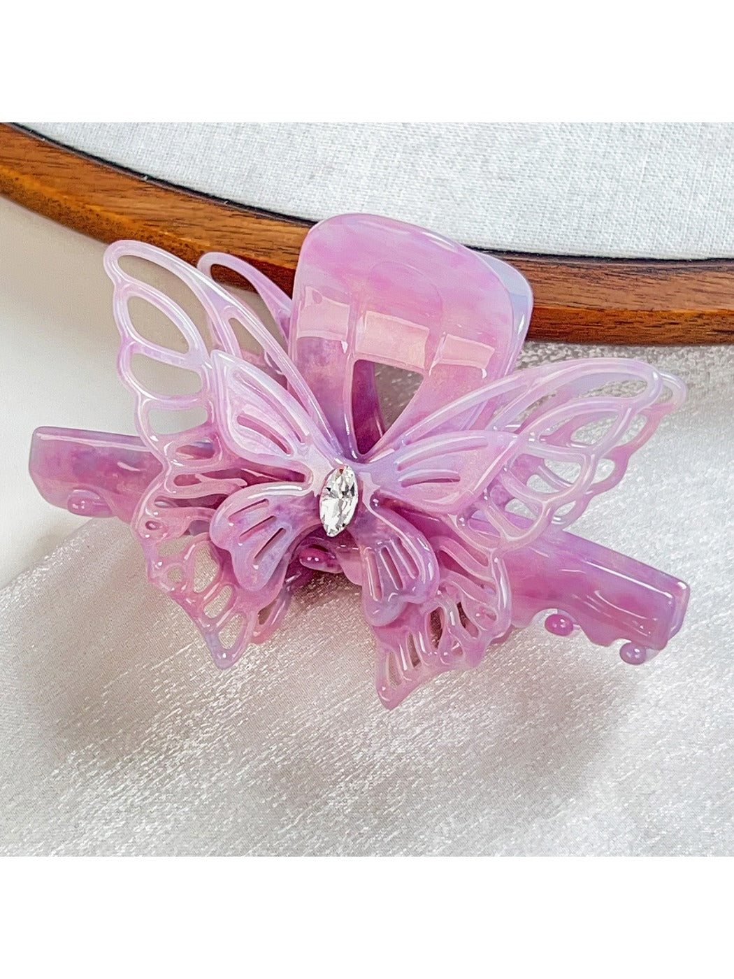 Beau elegant hair claw clip placed on a wooden surface with butterfly decoration
