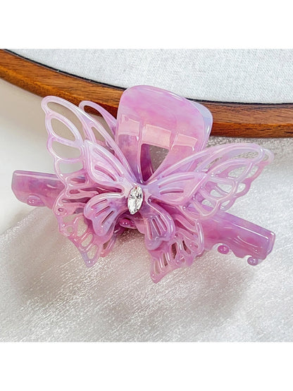 Beau elegant hair claw clip placed on a wooden surface with butterfly decoration