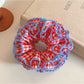 Close-up of red plaid ruffled scrunchie showing fabric texture and pattern