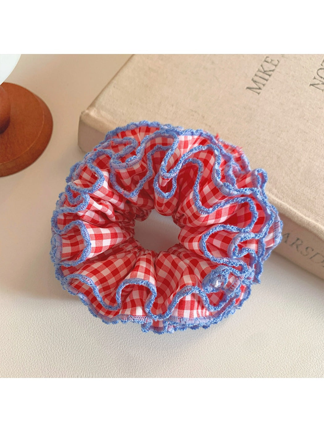 Close-up of red plaid ruffled scrunchie showing fabric texture and pattern