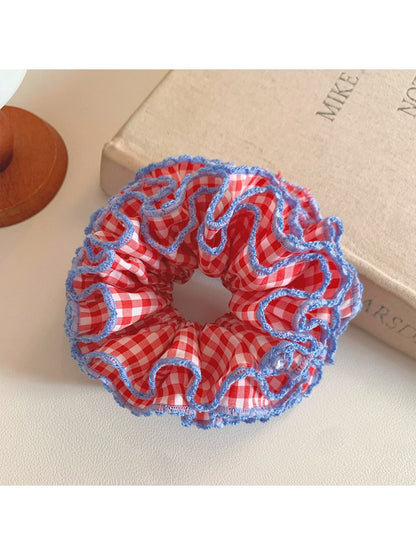 Close-up of red plaid ruffled scrunchie showing fabric texture and pattern