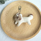 Keypus squirrel charm keychain shown with a blurred green outdoor background