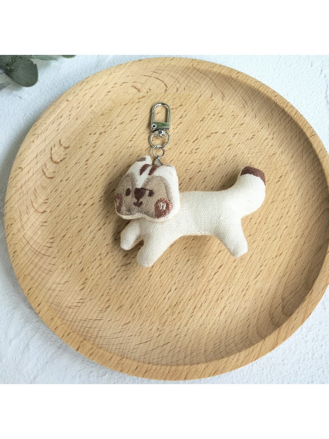 Keypus squirrel charm keychain shown with a blurred green outdoor background