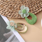 Sweet Raffia Flower Shaped Stud Earrings on a minimalist white jewelry stand