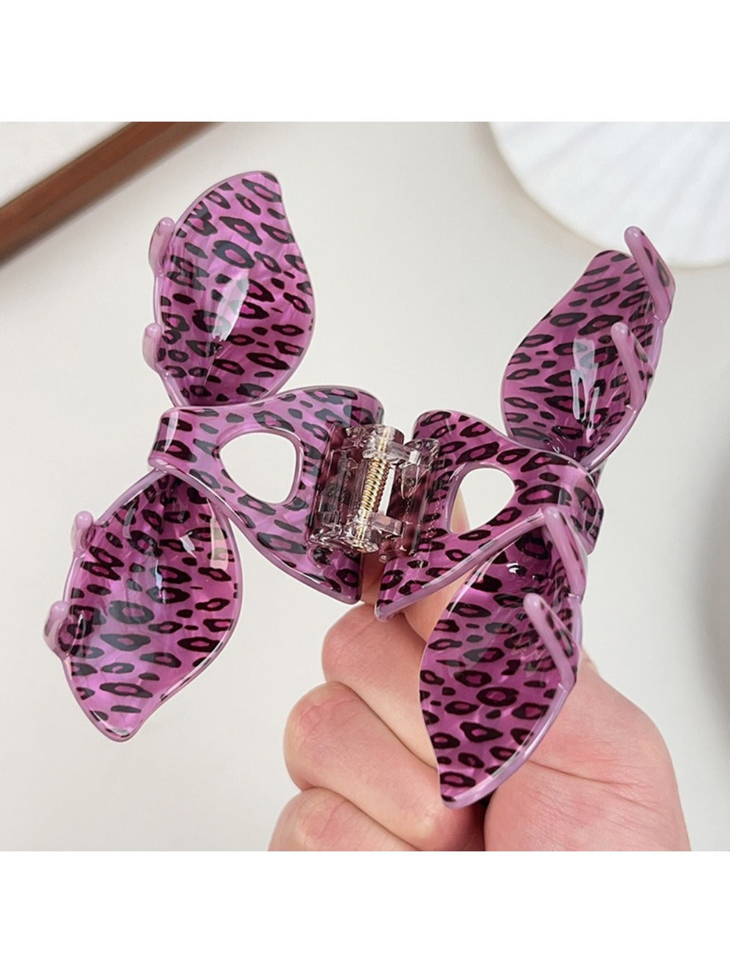 Beau leopard print claw clip held in hand displaying size and shape